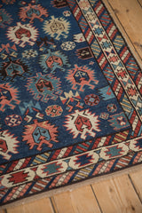 Geometric floral motifs and a serrated palmette border on an antique Caucasian rug.
