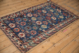Angled view of an antique Caucasian rug's unidirectional pattern on a sapphire blue field.