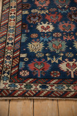 Angled view of a Caucasian rug's corner with a serrated palmette border and sapphire blue field.