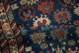 The rich, hand-knotted texture of an antique Caucasian rug featuring serrated floral and hook-latch motifs.