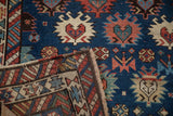 A folded corner reveals the reverse weave and rainbow checkered border of this antique Caucasian rug.