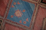 Close-up of a gem-tone blue medallion with detailed bird and floral motifs on a distressed Malayer rug.