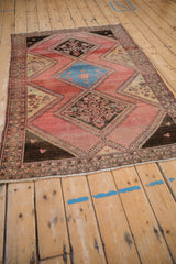 Angled perspective of a vintage Malayer rug highlighting its triple diamond medallions on a blush field.