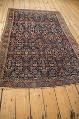 Fine antique Malayer rug showing its intricate Herati pattern and deep navy field from an angle.