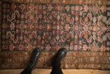 Distressed Hamadan rug, faded Herati pattern with charcoal, red, and blue motifs.