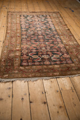 Secure fringed end of a vintage distressed Hamadan rug with charcoal and red Herati motif.