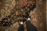 Antique Persian Malayer carpet: navy floral field, olive border, subtle wear, feet shown.