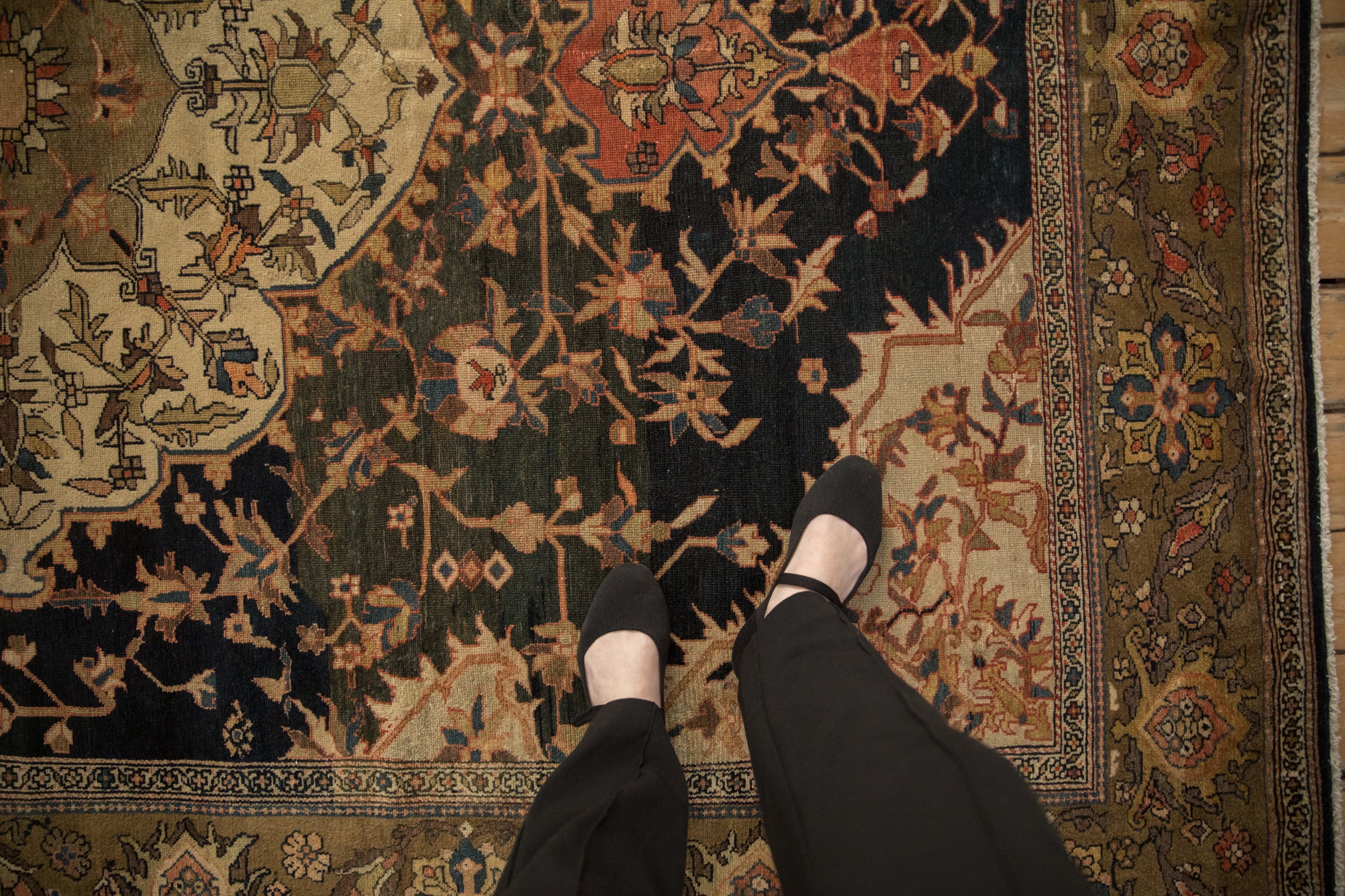 Antique Persian Malayer carpet: navy floral field, olive border, subtle wear, feet shown.