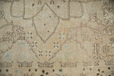 Distressed Kerman carpet's ivory wool pile texture with faded brown and powder blue floral details.