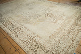 Distressed corner of an antique Kerman carpet, showing brown curvilinear borders and faint floral field.