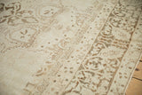 Distressed wool pile of an antique Kerman carpet with faded floral patterns in ivory and warm brown.