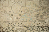 Distressed ivory Kerman carpet's field with sprawling coffee brown floral vines and soft blue highlights.