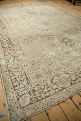 Distressed Antique Kerman carpet, detailed border with sprawling vines and soft ivory, brown tones.