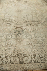 Soft, distressed wool pile of an antique Kerman carpet featuring faded scrolling vine designs.