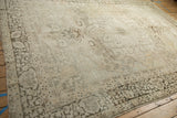 Antique Kerman carpet detail: distressed ivory and coffee brown floral pattern, visible wear, tattered edge.