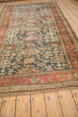 A perspective view highlighting the storied wear and Harshang design of an antique Bijar runner.