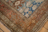 Corner detail of an antique Bijar rug with geometric borders in copper, brown, and dusty blue tones.