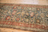 Angled view of an antique Bijar runner's distressed Harshang pattern in teal, red, and ivory.