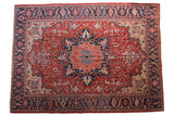 Vintage Heriz carpet with a bold navy medallion on a gem-tone red field and a detailed floral border.