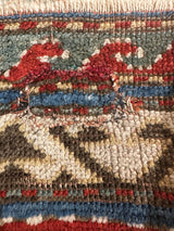 Hand-knotted pile close-up shows geometric gem-tone colors and original condition wear.