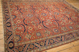 Angled view of a vintage Heriz carpet showing its crab-stylized motifs and navy pomegranate border.