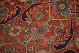 Close-up of a vintage Heriz carpet's pile showing floral motifs and serrated navy vines.