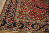 Corner detail of a vintage Heriz carpet showing the navy pomegranate and serrated leaf border.