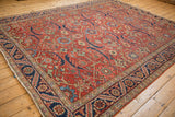 Angled view of the vintage Heriz carpet's allover field design with cherry red and navy blue tones.