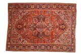 Vintage Heriz carpet with concentric geometric medallions in brick red, navy blue, and tangerine orange.