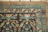 Close-up of a vintage Persian runner's corner, showing the boteh border design and low pile texture.