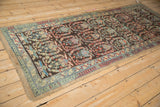 Angled view of a vintage runner showing repeating botehs and cloudbands on a chocolate brown field.