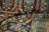 A fold in the vintage Northwest Persian rug reveals the textured pile and colorful boteh pattern details.