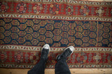 Even wear across the navy boteh field and red floral border of an antique Persian runner.