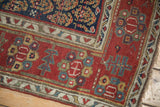 Corner of an antique Northwest Persian rug with a red floral border and ivory guard band.