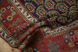 Textured pile of a folded antique Persian runner with navy boteh motifs and a red border.