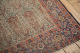 Antique Senneh rug's intricate paisley botehs, floral motifs, Herati border, showing wear.