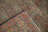 Antique Persian Senneh rug corner revealing intricate paisley botehs and worn foundation.