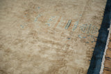 Low pile texture showing visible knot heads on the sand-colored field of an antique Deco carpet.