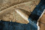 The low, textured pile and knot heads of a beige and cobalt blue antique Art Deco carpet.
