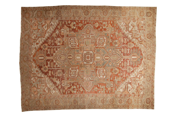 A vintage distressed Heriz carpet with a geometric medallion in dusty brick red, terra cotta, and platinum.