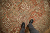 Worn, low-pile texture of a vintage Heriz carpet showing its geometric design in dusty red, sage, and platinum.