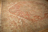 Angled view of a distressed Heriz carpet's geometric border in a terra cotta and sage palette.
