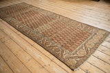 Angled view of a distressed Hamadan runner showing its dynamic boteh pattern and horizontal abrash.