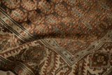 Detailed view of a folded vintage Hamadan rug showing textured botehs and the serrated leaf border.