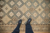 Top-down view of a distressed Sivas carpet's hook-and-latch diamond pattern in beige and slate.