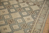 Detailed view of diamond-shaped medallions with hook-and-latch outlines on a distressed vintage rug.