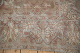 Detailed view of the distressed antique carpet's worn pile and serrated leaf border.