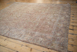 Angled view of an antique Sultanabad carpet highlighting its time-softened texture and faded floral pattern.