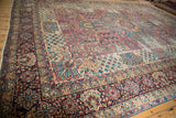 Fine floral motifs on deep blue border and worn ivory field of antique Kerman rug.