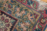 Detail of an antique Kerman carpet showing wear to foundation, knot heads, and tattered fringe.